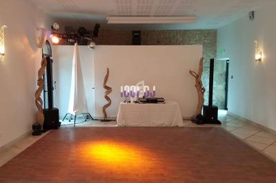 Salle vide avec parquet, éclairage tamisé, table de DJ équipée et décorations en bois torsadé.