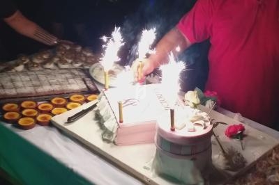 Gâteau décoré avec des bougies étincelantes sur une table garnie de desserts variés lors d'une célébration.