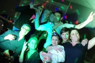 Un groupe de personnes posant joyeusement dans une ambiance festive avec des lumières colorées.