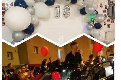 Décoration d'anniversaire avec ballons et chiffre 18, et célébration en extérieur avec voiture décorée et invités.