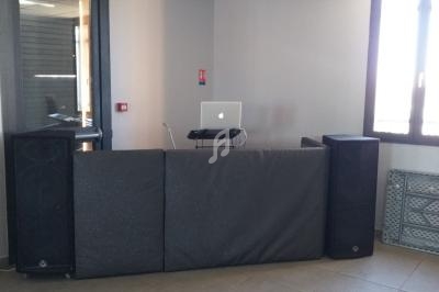 Poste de DJ avec ordinateur portable sur une table derrière des enceintes et des panneaux insonorisants dans une pièce…