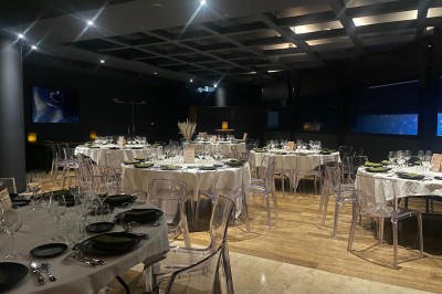 Tunnel d'aquarium avec un grand bassin à droite, éclairages colorés et écran lumineux sur le mur gauche.