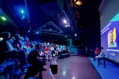 Tunnel d'aquarium avec un grand bassin à droite, éclairages colorés et écran lumineux sur le mur gauche.