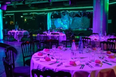 Tunnel d'aquarium avec un grand bassin à droite, éclairages colorés et écran lumineux sur le mur gauche.