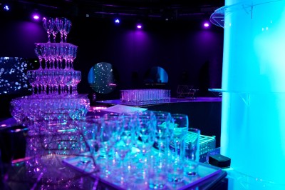 Tunnel d'aquarium avec un grand bassin à droite, éclairages colorés et écran lumineux sur le mur gauche.