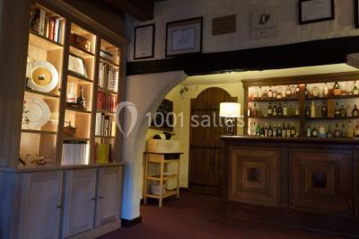 Table dressée avec des verres, couverts et serviettes, entourée de chaises colorées dans une salle lumineuse avec…