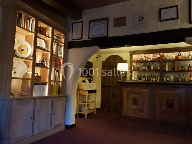 Intérieur d'un bar avec un comptoir en bois, une étagère éclairée contenant des livres et des objets décoratifs.
