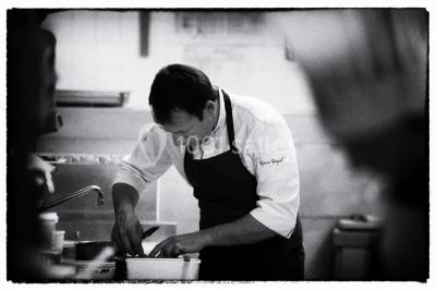 Table dressée avec des verres, couverts et serviettes, entourée de chaises colorées dans une salle lumineuse avec…