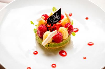 Table dressée avec des verres, couverts et serviettes, entourée de chaises colorées dans une salle lumineuse avec…