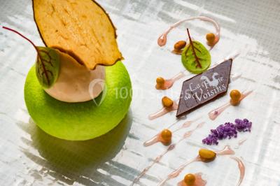 Table dressée avec des verres, couverts et serviettes, entourée de chaises colorées dans une salle lumineuse avec…