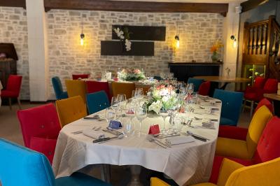 Table dressée avec des verres, couverts et serviettes, entourée de chaises colorées dans une salle lumineuse avec…
