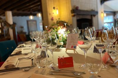 Table dressée avec des verres, couverts et serviettes, entourée de chaises colorées dans une salle lumineuse avec…