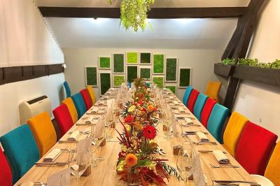 Table dressée avec des verres, couverts et serviettes, entourée de chaises colorées dans une salle lumineuse avec…