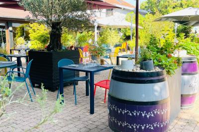 Table dressée avec des verres, couverts et serviettes, entourée de chaises colorées dans une salle lumineuse avec…