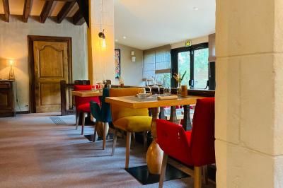 Table dressée avec des verres, couverts et serviettes, entourée de chaises colorées dans une salle lumineuse avec…