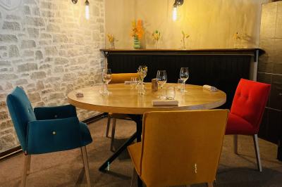 Table dressée avec des verres, couverts et serviettes, entourée de chaises colorées dans une salle lumineuse avec…