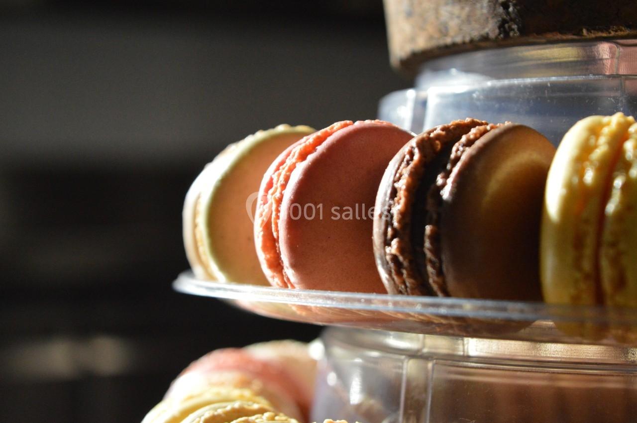 Assortiment de macarons colorés disposés sur un présentoir transparent, éclairés par une lumière naturelle.