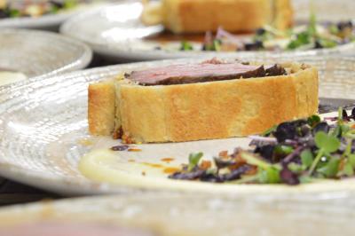 Table dressée avec des verres, couverts et serviettes, entourée de chaises colorées dans une salle lumineuse avec…