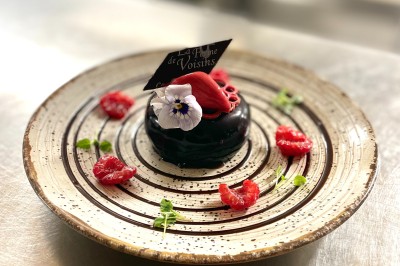 Table dressée avec des verres, couverts et serviettes, entourée de chaises colorées dans une salle lumineuse avec…