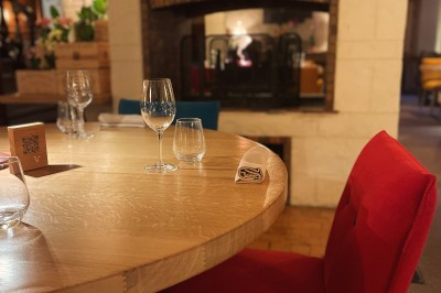 Table dressée avec des verres, couverts et serviettes, entourée de chaises colorées dans une salle lumineuse avec…