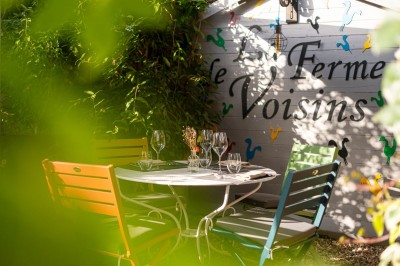 Table dressée avec des verres, couverts et serviettes, entourée de chaises colorées dans une salle lumineuse avec…