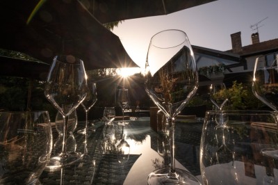 Table dressée avec des verres, couverts et serviettes, entourée de chaises colorées dans une salle lumineuse avec…