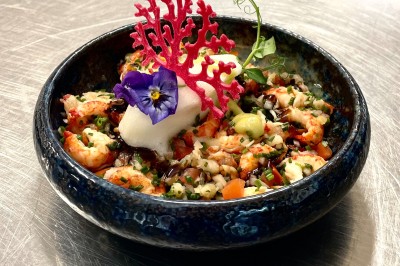 Table dressée avec des verres, couverts et serviettes, entourée de chaises colorées dans une salle lumineuse avec…