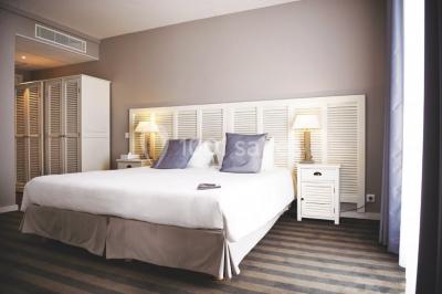 Vue aérienne d'un bâtiment en bord de mer entouré de champs et de vignobles sous un ciel dégagé.