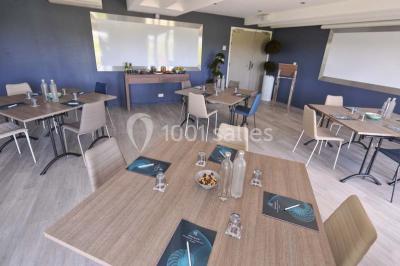 Vue aérienne d'un bâtiment en bord de mer entouré de champs et de vignobles sous un ciel dégagé.