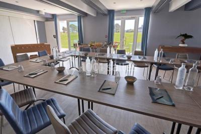 Vue aérienne d'un bâtiment en bord de mer entouré de champs et de vignobles sous un ciel dégagé.