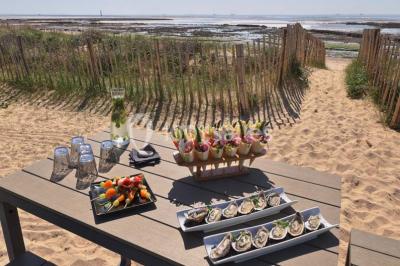 Vue aérienne d'un bâtiment en bord de mer entouré de champs et de vignobles sous un ciel dégagé.
