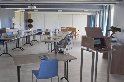 Vue aérienne d'un bâtiment en bord de mer entouré de champs et de vignobles sous un ciel dégagé.