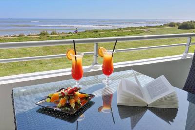 Vue aérienne d'un bâtiment en bord de mer entouré de champs et de vignobles sous un ciel dégagé.