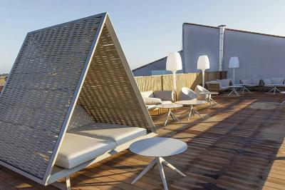 Vue aérienne d'un bâtiment en bord de mer entouré de champs et de vignobles sous un ciel dégagé.