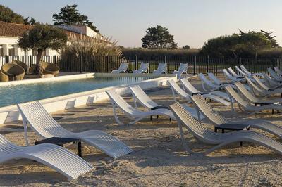 Vue aérienne d'un bâtiment en bord de mer entouré de champs et de vignobles sous un ciel dégagé.