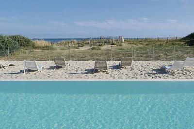 Vue aérienne d'un bâtiment en bord de mer entouré de champs et de vignobles sous un ciel dégagé.