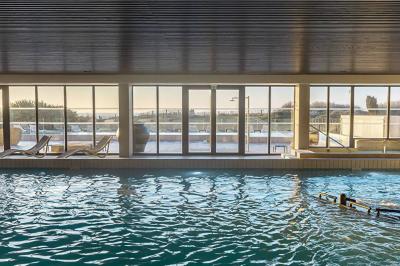 Vue aérienne d'un bâtiment en bord de mer entouré de champs et de vignobles sous un ciel dégagé.