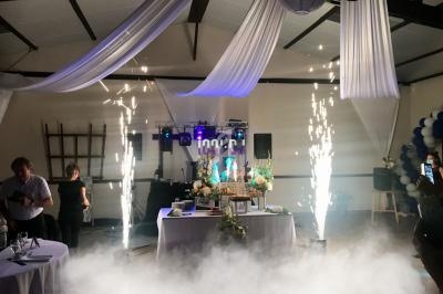 Effets pyrotechniques et décoration lumineuse autour d'une table festive dans une salle ornée de drapés blancs.