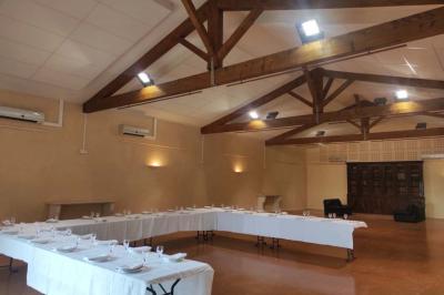 Un jardin verdoyant avec pelouse, arbustes, olivier central et allées bordées de végétation sous un ciel dégagé.