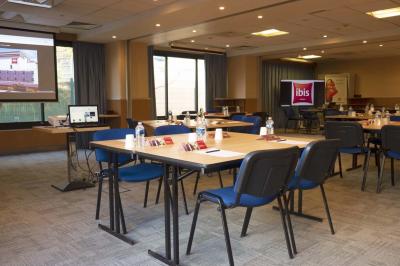 Chambre d'hôtel lumineuse avec un lit double, une fenêtre avec rideaux rouges et un bureau en bois clair.