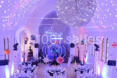 Salle de réception lumineuse avec bar central circulaire, tables hautes et éclairage coloré.