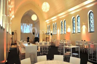 Salle de réception lumineuse avec bar central circulaire, tables hautes et éclairage coloré.