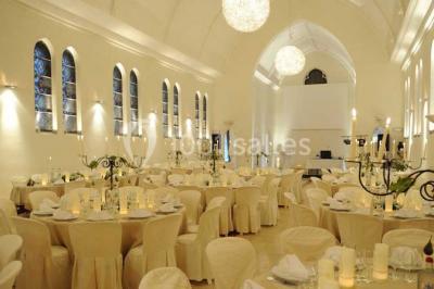 Salle de réception lumineuse avec bar central circulaire, tables hautes et éclairage coloré.