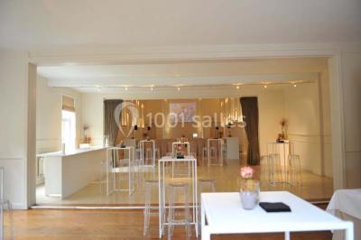 Salle de réception lumineuse avec bar central circulaire, tables hautes et éclairage coloré.