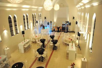 Salle de réception lumineuse avec bar central circulaire, tables hautes et éclairage coloré.