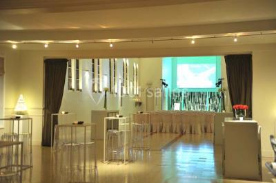 Salle de réception lumineuse avec bar central circulaire, tables hautes et éclairage coloré.