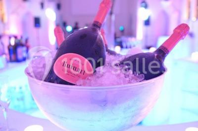 Salle de réception lumineuse avec bar central circulaire, tables hautes et éclairage coloré.