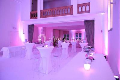 Salle de réception lumineuse avec bar central circulaire, tables hautes et éclairage coloré.