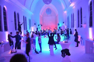 Salle de réception lumineuse avec bar central circulaire, tables hautes et éclairage coloré.