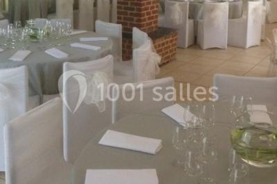 Table élégamment dressée avec nappes blanches, vaisselle raffinée, bougies allumées et décoration florale.